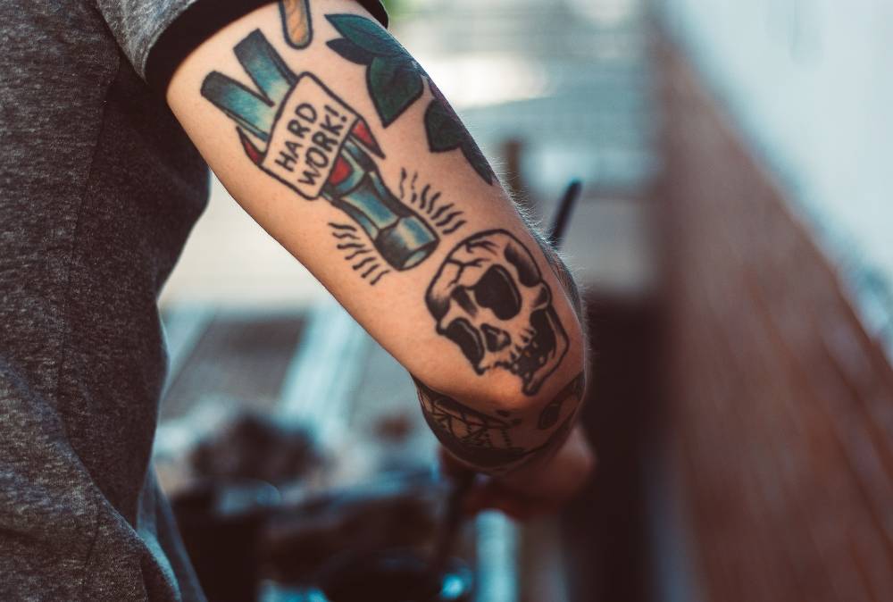 Tattoo on man's forearm saying "Hard Work!"